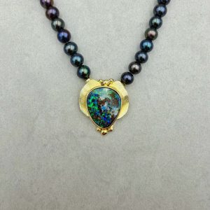 Handgefertigter Unikat-Anhänger aus 585/-Gelbgold mit einem australischen Boulder Opal (ca. 20x16.5mm) mit wunderschönem, vorwiegend blauem und grünem Farbenspiel. Kombiniert mit einer Kette aus schwarzen, bunt-changierenden Süßwasserzuchtperlen. Gesamtlänge: 46,5cm