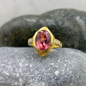 Handgefertigter Unikat-Ring aus 585/-Gelbgold mit einem pinken Turmalin (oval, facettiert, ca.11x8mm), seitlich kombiniert mit 6 Diamanten im Brillantschliff, gesamt 0.12ct. TW/vsi.