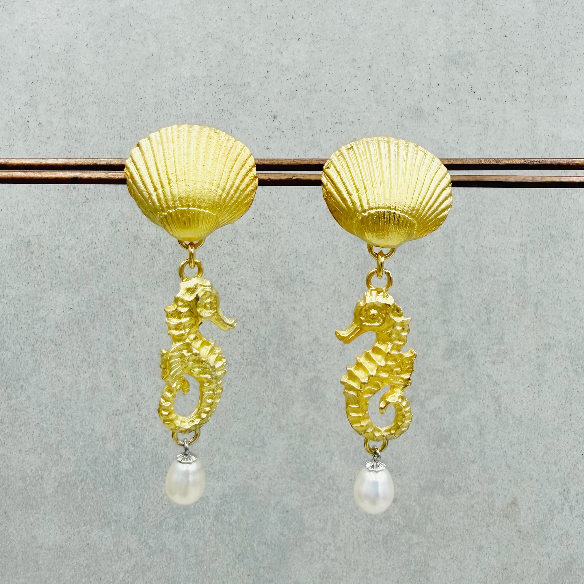 Ohrhänger mit Muscheln, Seepferdchen und kleinen Perlen. Die schönen Strukturen der Oberflächen diese maritimen Lieblinge strahlen besonders im Kontrast zu den glatten, tropenförmigen Perlen. Material: 925/-Silber, vergoldet Gesamtlänge: ca. 5cm Muschel: ca. 14x17mm Seepferdchen: ca. 21x10mm Süßwasserzuchtperlen: ca. 7x5.5mm