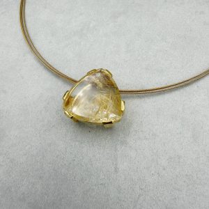 Handgefertigter Anhänger aus 585/- Gelbgold mit einem Fair Trade Rutilquarz: 27,02ct. (ca.24,5mm) in einem abgerundetem Dreieck als Spiegelschliff. Durch den Schliff kommen die feinen Futil-Nadeln im Inneren des Quarzes besonders schön raus - ein Wunderwerk der Natur! Fair funkelt mehr: der Edelstein kommt aus fairem und nachhaltigem Abbau. Der Anhänger ist kombiniert mit einem vergoldetem Stahlreif (42cm).